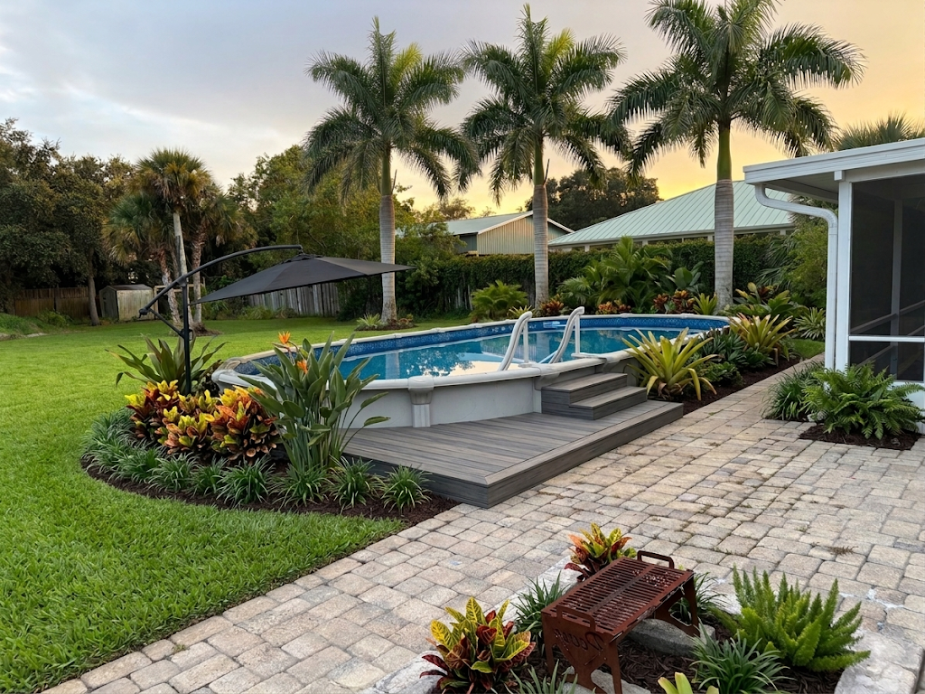 Oval above-ground pool with a composite deck, paver patio, and tropical landscaping in a back yard in Cocoa, Florida